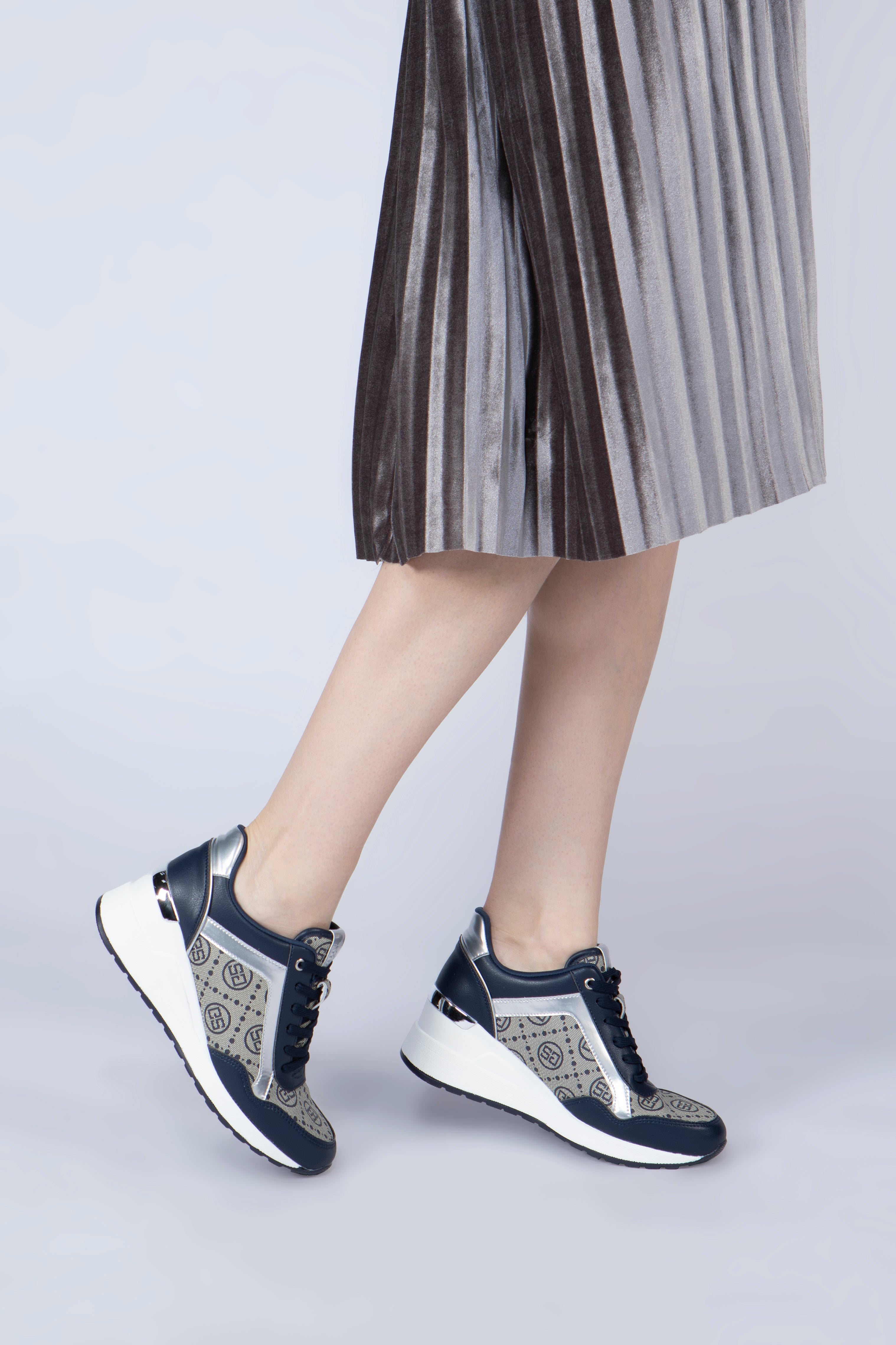 صورة جانبية لقدم شابة ترتدي حذاء ساغا الرياضي النسائي بلون كحلي وفضي