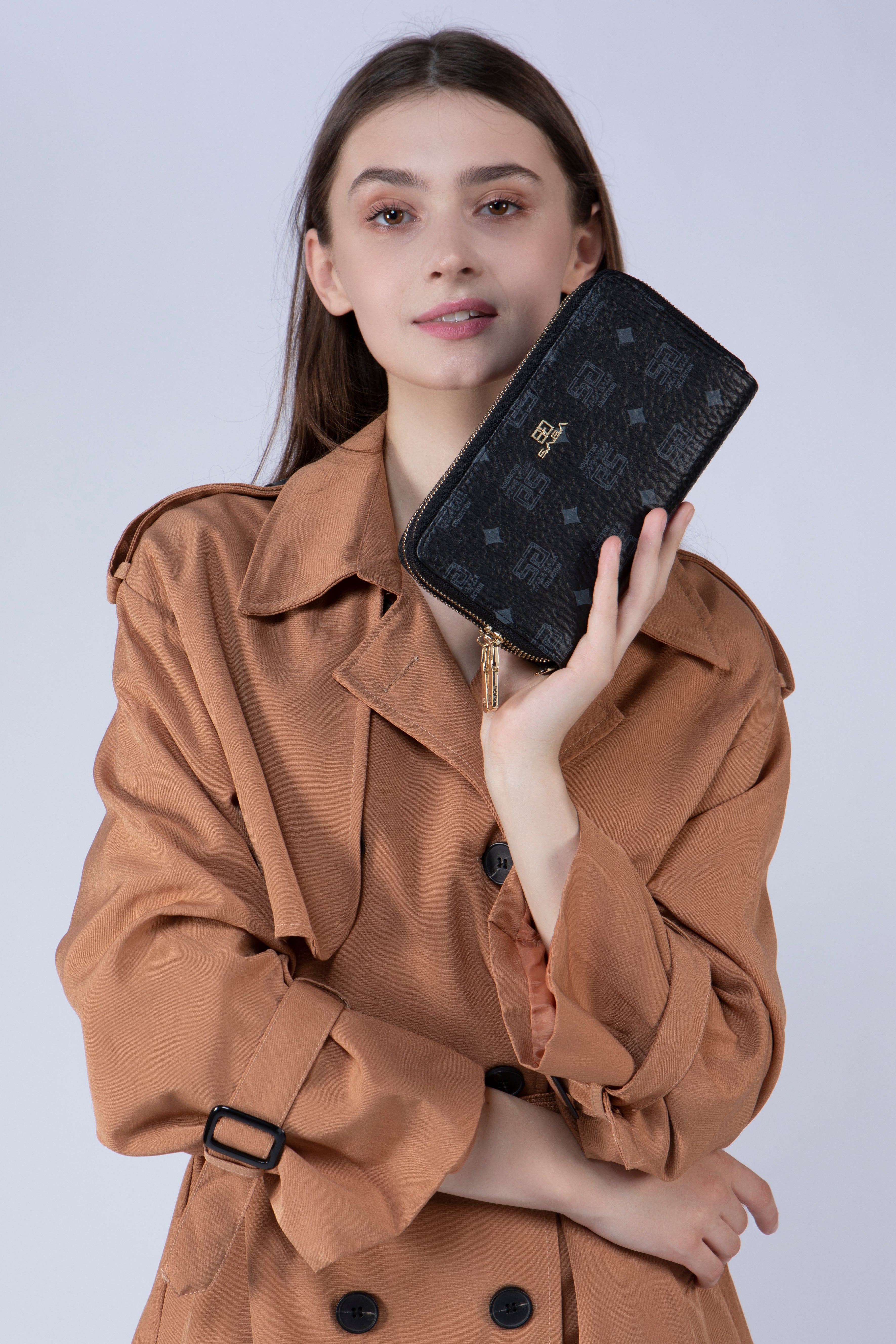 بنت تحمل محفظة نسائية من ساغا لونها أسود مع شعار ساغا مطبوع على المحفظة 