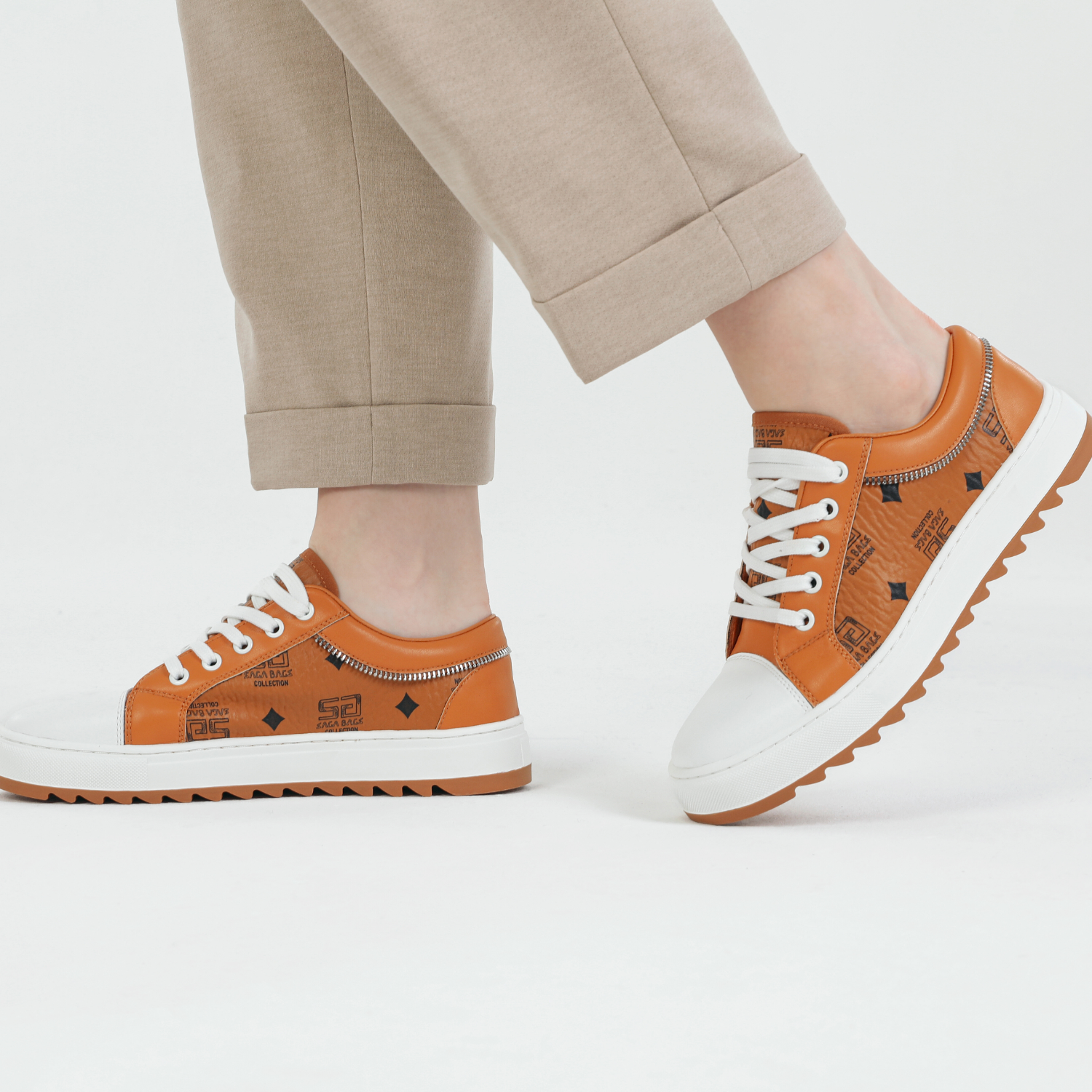 زاوية خلفية لحذاء رياضي برتقالي من ساغا يظهر النعل المتعرج والسحاب الجانبي لسهولة الاستخدام